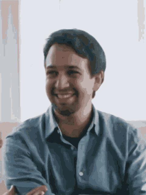 a man wearing a blue shirt is smiling with his arms crossed