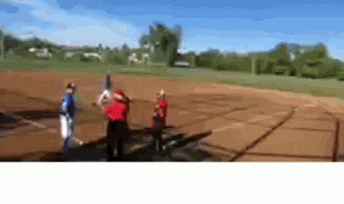 a blurry picture of people playing baseball on a field with trees in the background