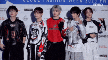 a group of young men standing in front of a sign that says seoul fashion week