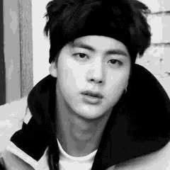 a black and white photo of a young man wearing a headband and jacket .
