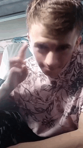 a young man in a floral shirt is giving the peace sign