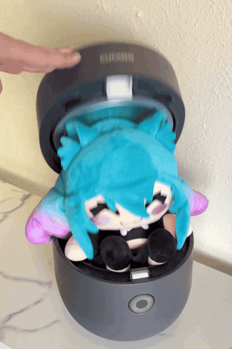 a stuffed animal with blue hair and purple ears sits in a black box with the word turbo on it
