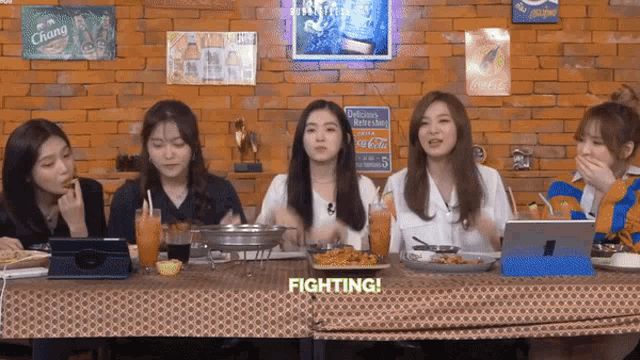 a group of girls are sitting at a table with a sign that says fighting