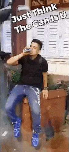 a man is drinking a can of soda while sitting on a brick wall .