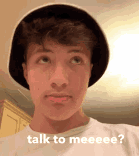 a young man wearing a hat and a white t-shirt is asking to talk to me .