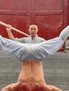 a man is doing a handstand on a set of stairs while holding a stick .