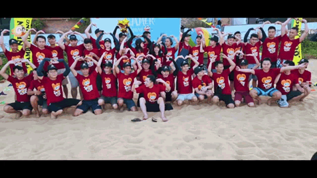 a group of people posing for a picture on a beach wearing red shirts that say summer