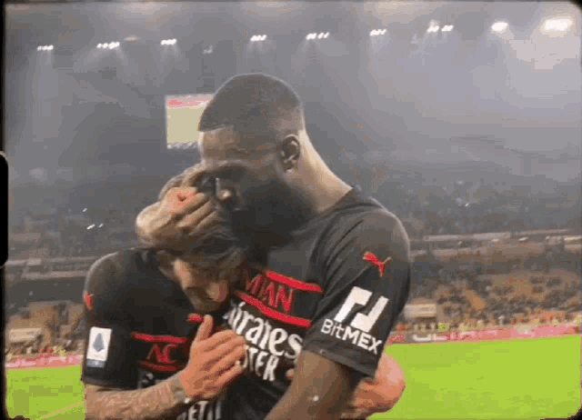 two soccer players hugging each other with one wearing a jersey that says bitmex