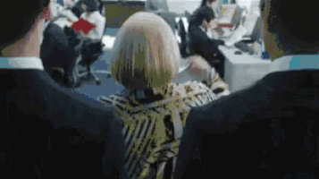 a group of people are sitting in a room looking at a computer screen .