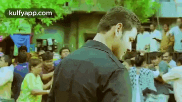a man in a black jacket is standing in front of a crowd .