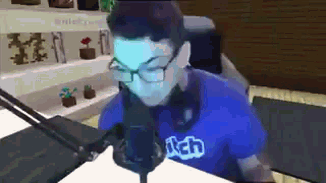 a man wearing glasses is sitting in front of a microphone in a room .
