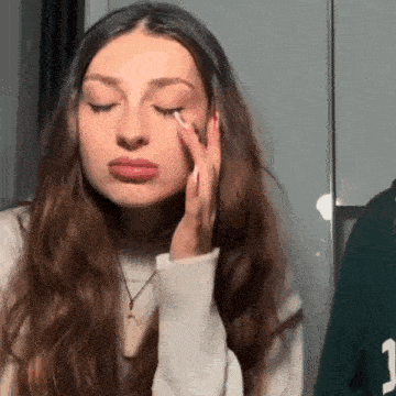 a woman is applying eye shadow to her eye while looking at herself in the mirror .
