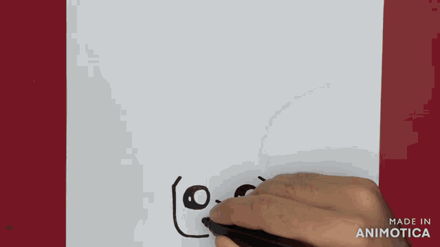 a person is drawing a face with a pen on a piece of paper