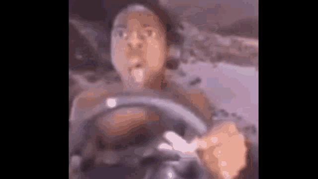a man is driving a car with a steering wheel .