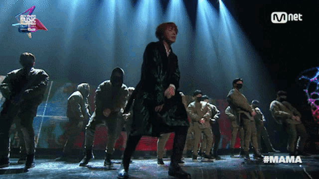 a group of people are dancing on a stage with the word mama on the bottom right