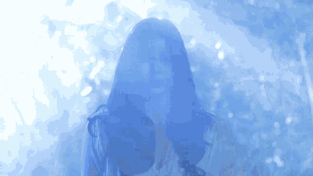 a woman with long hair is standing in a dark room with a blue light behind her