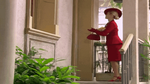 a woman in a red suit and red hat is standing on the stairs