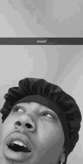 a black and white photo of a man wearing a hat with the word mood written on the bottom .