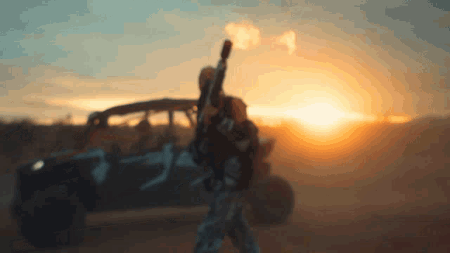 a blurred image of a man holding a gun in front of a sunset