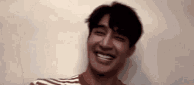 a man in a striped shirt is smiling with his eyes closed and his mouth open .