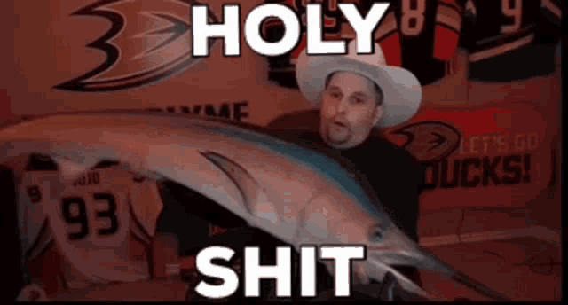 a man in a cowboy hat is holding a fish with the words holy shit written on it