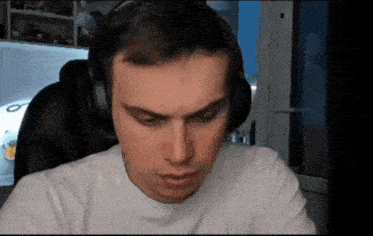 a man wearing headphones and a white shirt looks at the camera