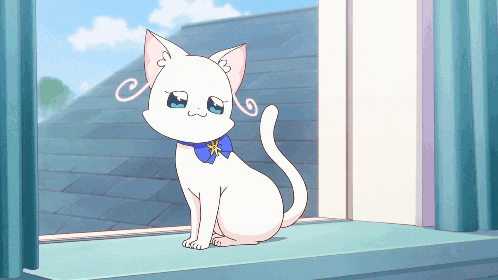 a white cat sitting on a window sill with a blue bow around its neck