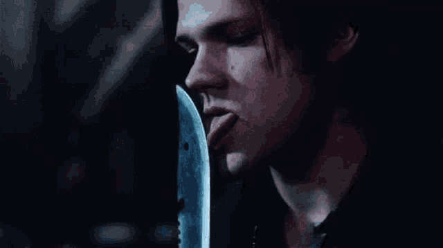 a man is licking a knife with his tongue .