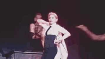 a woman in a white shirt is dancing on a stage