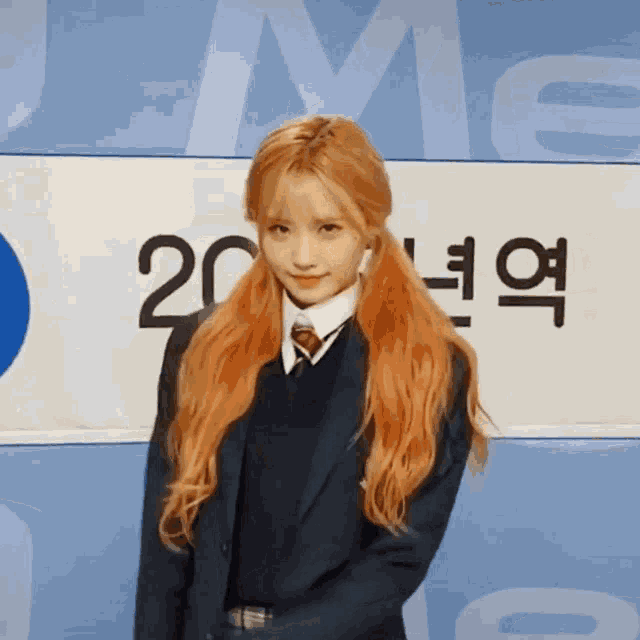 a girl in a school uniform stands in front of a sign with the number 20 on it