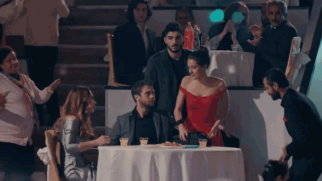 a woman in a red dress sits at a table next to a man in a suit