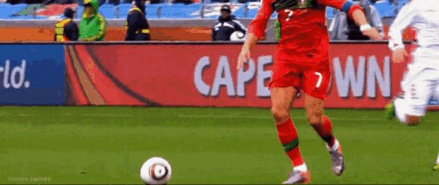 a soccer player kicking a ball in front of a cape town banner