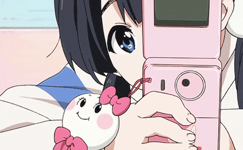 a girl is holding a pink flip phone and a stuffed animal