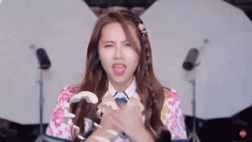 a girl in a floral shirt is making a funny face while holding a piece of paper .