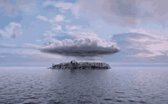 a small island in the middle of the ocean with a cloud in the sky