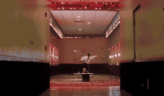 a man is standing in a hallway with a red exit sign