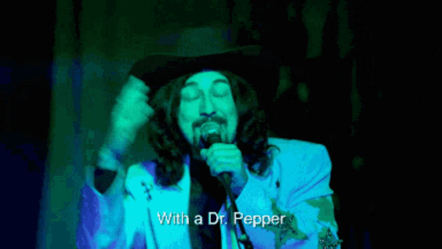 a man in a cowboy hat sings into a microphone with the words with a dr pepper below him