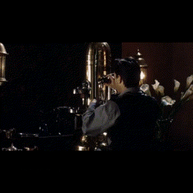 a man is standing in front of a saxophone in a dark room .