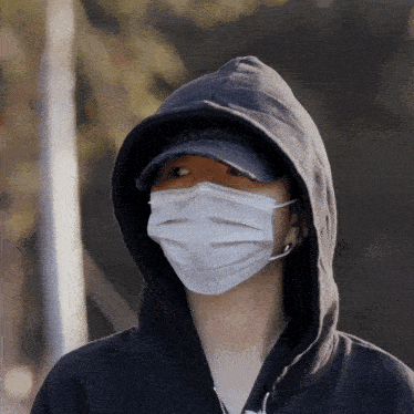 a person wearing a black hoodie and a white mask