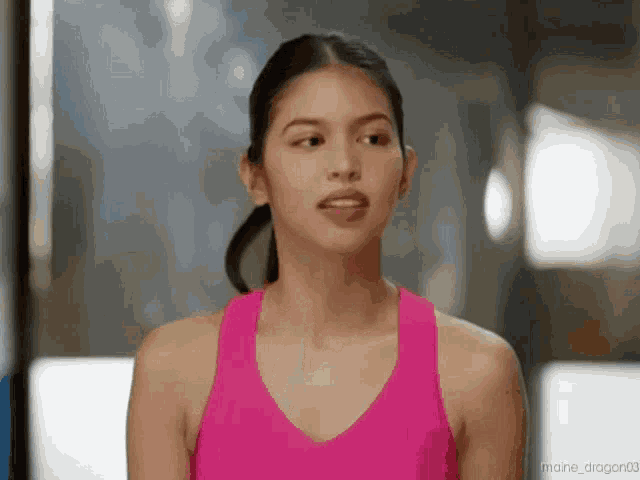 a woman wearing a pink tank top is making a funny face