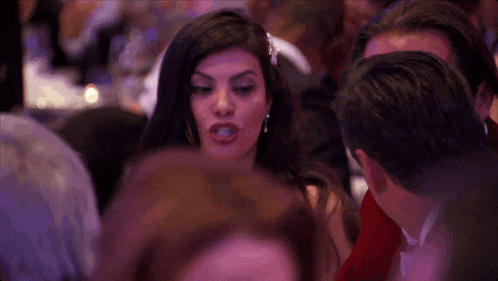 a woman in a red dress stands in a crowd of people
