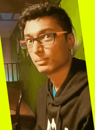 a young man wearing glasses and a black hoodie with the letter m on the front