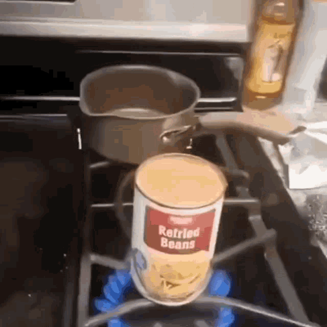 a can of refried beans is sitting on a stove next to a pot