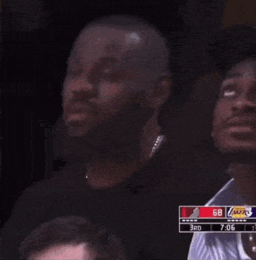 a man wearing a denim tears hat sits in the stands watching a basketball game