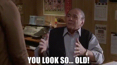 an older man is sitting at a desk in an office talking to another man and says `` you look so ... old ! ''