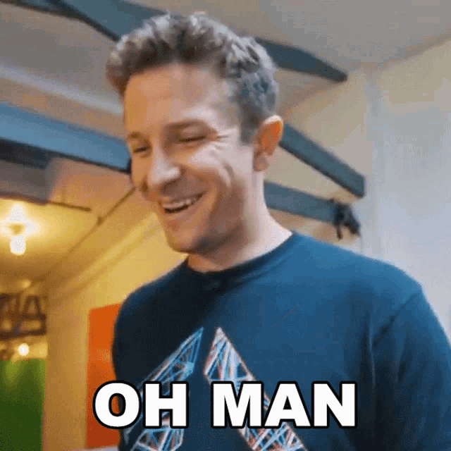 a man in a blue shirt is smiling and says " oh man "