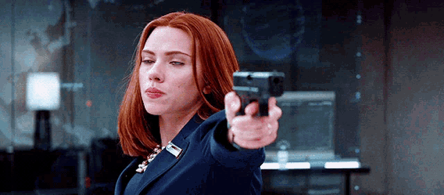 a woman with red hair is pointing a gun at someone .