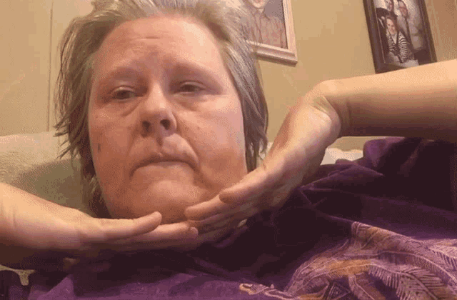 a woman is laying on a couch with her hands on her face