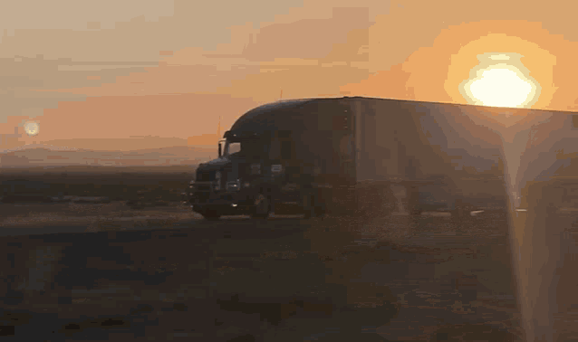 a semi truck is driving on a road at sunset
