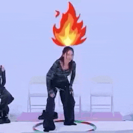 a woman is dancing with a fire on her head and a hula hoop .